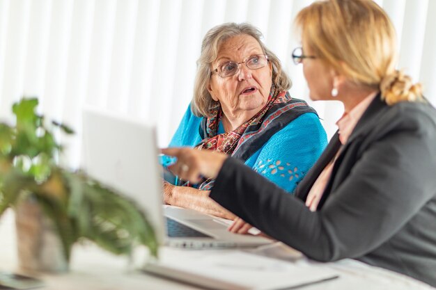 Kobieta pomagająca starszej dorosłej kobiecie na laptopie