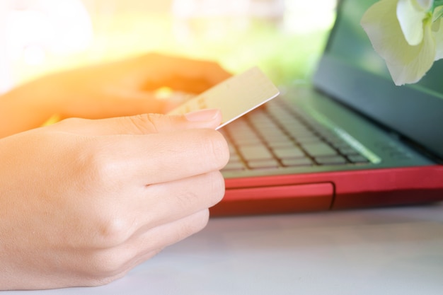 Kobieta posiadania karty kredytowej z laptopem w kawiarni z promieniami słońca promieniami światła w mornging, Zakupy online
