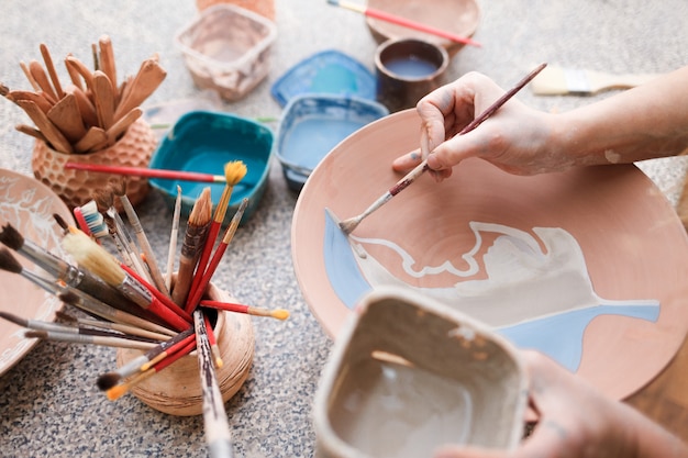 Zdjęcie kobieta potter maluje talerz ceramiczny.