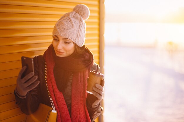 Zdjęcie kobieta pozuje z telefonem i kawą w zimnej zimie