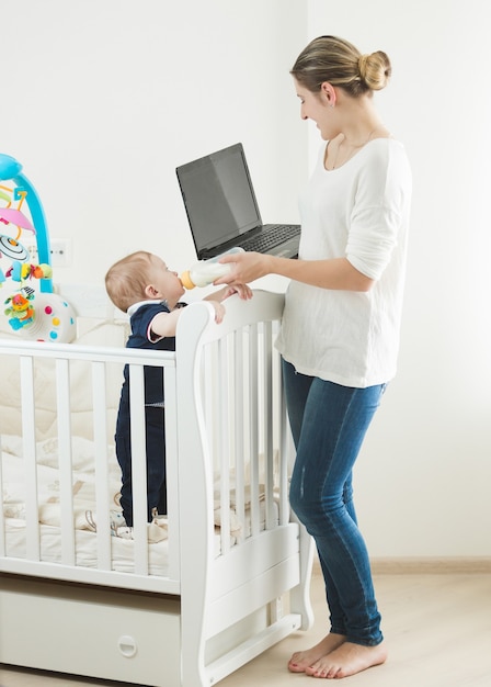 Kobieta pracująca na laptopie i opiekująca się dzieckiem