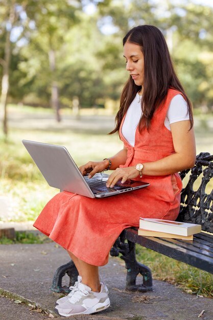Kobieta Pracująca W Parku Z Laptopem Siedząca Na ławce Wśród Drzew