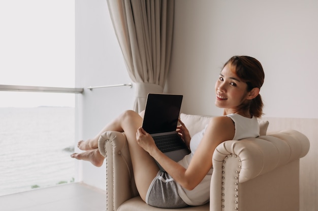 Kobieta pracuje i relaksuje się z laptopem na kanapie koncepcja pracy z hotelu