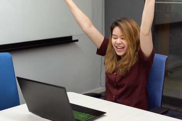 Kobieta pracuje laptopem w biurze z szczęśliwym