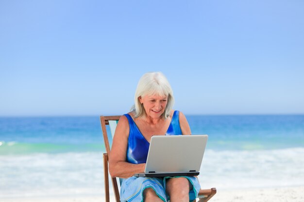 Kobieta pracuje na jej laptopie na plaży