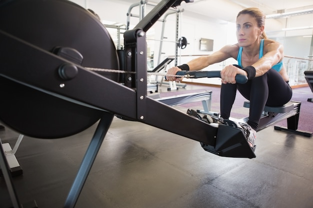 Kobieta pracuje na sprawności fizycznej maszynie przy gym