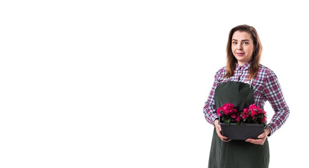 Kobieta profesjonalny ogrodnik lub kwiaciarnia w fartuchu trzyma kwiaty w doniczce na białym tle