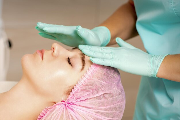 Kobieta przechodzi zabieg kosmetyczny podczas dotykania się kosmetologa w rękawiczkach medycznych