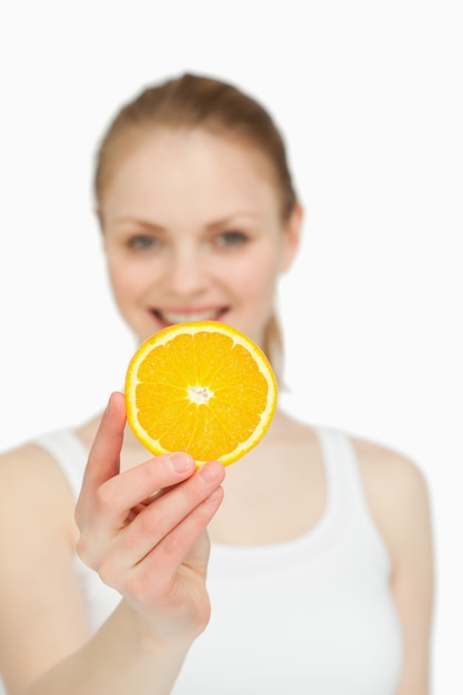Kobieta przedstawiająca pomarańczowy kawałek jednocześnie uśmiechając się