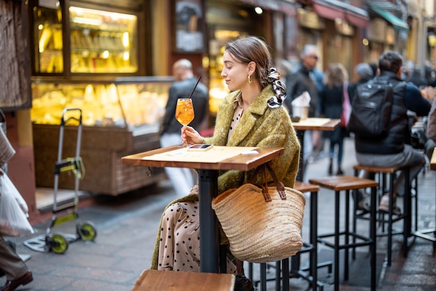 Kobieta przy koktajlu w barze na świeżym powietrzu lub restauracji w bolonii