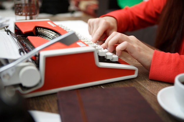 Kobieta przy stole pisząca na maszynie do pisania
