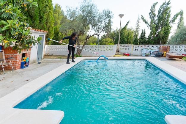 Kobieta przygotowująca i czyszcząca basen do strefy pływackiej z odkurzaczem wodnym w rękach