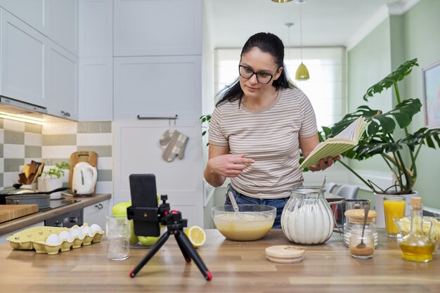 Kobieta przygotowująca szarlotkę w domu w kuchni rozmawia online za pomocą rozmowy wideo