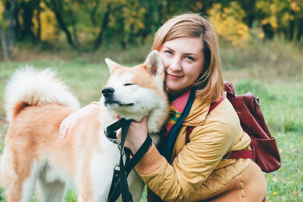 Kobieta przytula psa husky białego imbiru w parku jesienią.