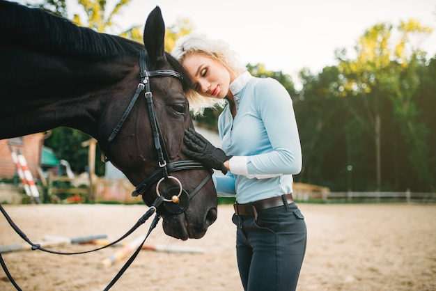 Kobieta przytula swojego konia, przyjaźń, jazda konna. Jeździectwo, młoda kobieta i piękny ogier, zwierzę hodowlane
