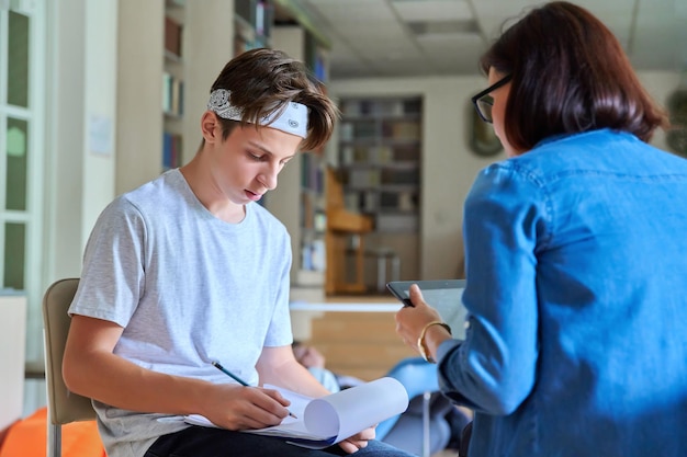 Kobieta psycholog szkolny rozmawia i pomaga uczniowi nastoletniemu mężczyźnie