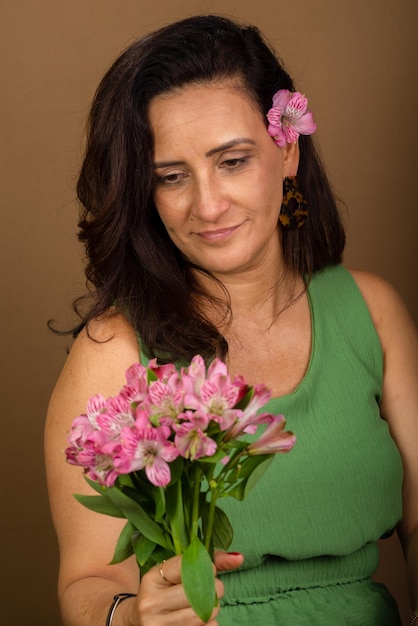 Zdjęcie kobieta rasy kaukaskiej bardzo szczęśliwa i zakochana trzymająca bukiet kwiatów izolowana na brązowym tle