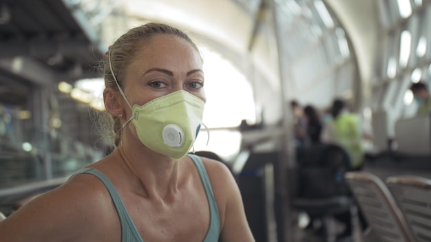 Kobieta rasy kaukaskiej na lotnisku w ochronnej masce medycznej na głowie na tle samolotu Koncepcja zdrowie bezpieczeństwo ochrona przed wirusami koronawirus epidemia sarscov2 covid19 2019ncov