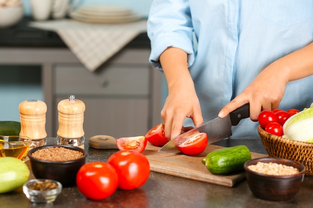 Kobieta ręce cięcia pomidorów przy stole w kuchni