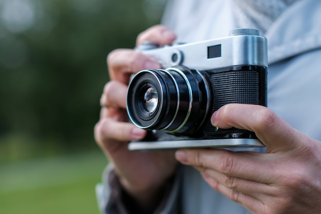 Kobieta ręce, trzymając aparat fotograficzny retro przed sobą i robienia zdjęć.