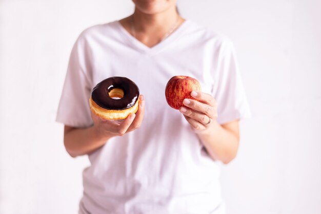Kobieta Ręce Trzymając Czerwone Jabłko I Pieczony Pączek Czekoladowy Na Białym Tle, Zdrowa Dieta, Koncepcja Diety