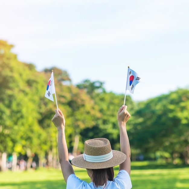 Kobieta ręka trzyma flagę Korei na tle przyrody Narodowa Fundacja Gaecheonjeol naród publiczny święto narodowego dnia wyzwolenia Korei i koncepcje szczęśliwego świętowania