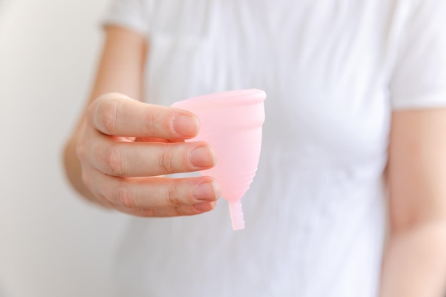 Kobieta ręka trzyma różowy kubek menstruacyjny na białym tle kobieta nowoczesna alternatywa eko ginek...