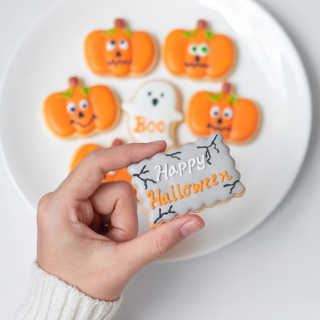 Kobieta ręka trzyma śmieszne Halloween Cookie podczas picia kawy. Happy Halloween Day, Trick or Threat, Hello October, jesień jesień, tradycyjna, imprezowa i świąteczna koncepcja