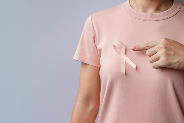 Kobieta ręka trzyma wstążkę brzoskwiniową we wrześniu miesiąc świadomości raka macicy Opieka zdrowotna i koncepcja światowego dnia raka
