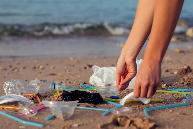 Zdjęcie kobieta ręka zbierająca plastikowe butelki do czyszczenia na plaży, koncepcja wolontariusza