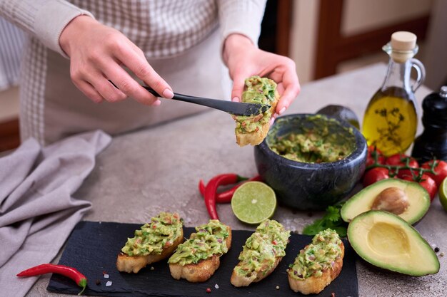 Zdjęcie kobieta robi bruschettę ze świeżo zrobionym guacamole w domowej kuchni