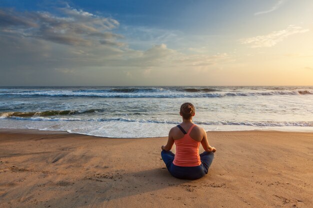 Kobieta robi joga oudoors przy plażą - Padmasana lotosu poza