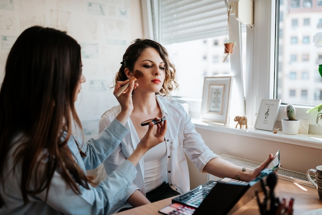 Kobieta robi makeup na jej przyjacielu w domu.