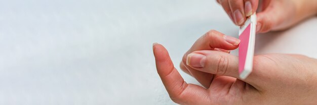 Kobieta robi manicure z pilnikiem do paznokci. Koncepcja pielęgnacji paznokci w domu.