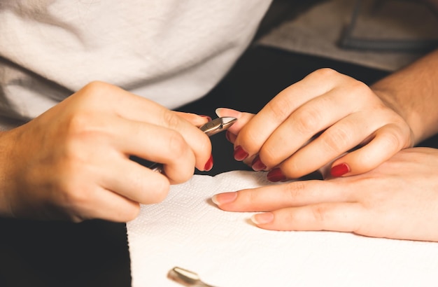 Kobieta robi manicure. Zabiegi salonowe w domu. Piękne dłonie i paznokcie.