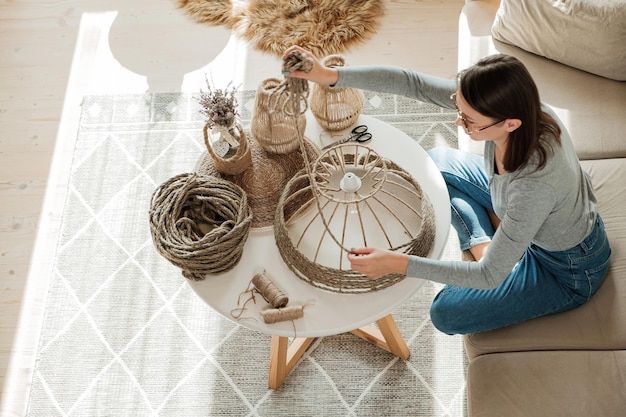 Zdjęcie kobieta robi ręcznie robioną lampę diy z liny jutowej w domu