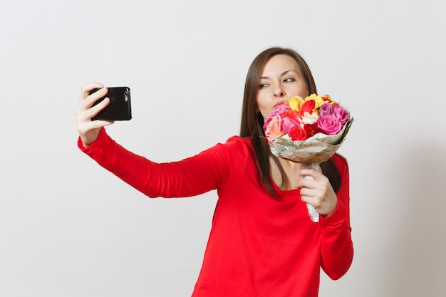 Kobieta robi selfie kaczka twarz na telefon komórkowy z bukietem pięknych kwiatów na białym tle. Skopiuj miejsce na reklamę. Walentynki, Międzynarodowy Dzień Kobiet, koncepcja świąteczna