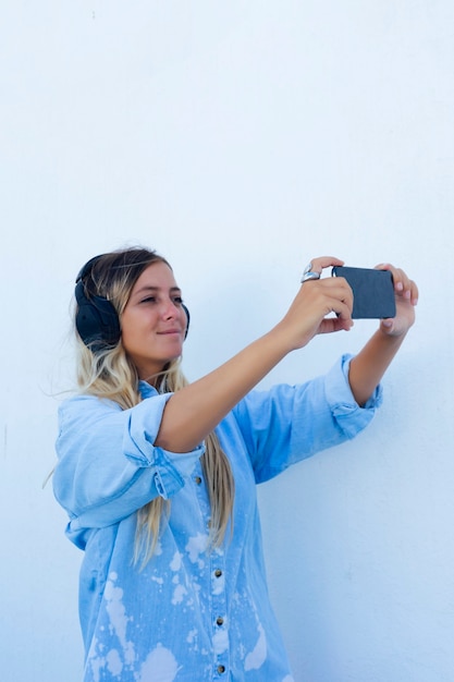 Zdjęcie kobieta robi selfie podczas słuchania muzyki przez telefon. białe tło