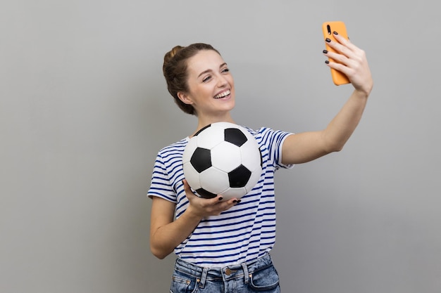 Kobieta robi selfie podczas wideorozmowy lub transmisji na żywo z piłką w ręku