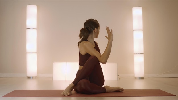 Kobieta robi siedzącej skręceniu kręgosłupa pozie na macie Dysponowana dziewczyna wykonuje jogę w studiu
