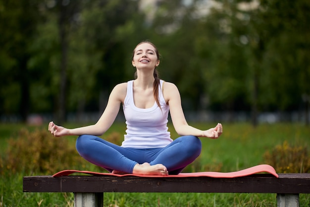Kobieta robi trening jogi siedząc na ławce w parku