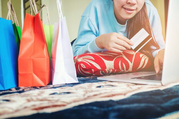 Kobieta robi zakupy online używać laptop z kredytową kartą cieszy się w domu