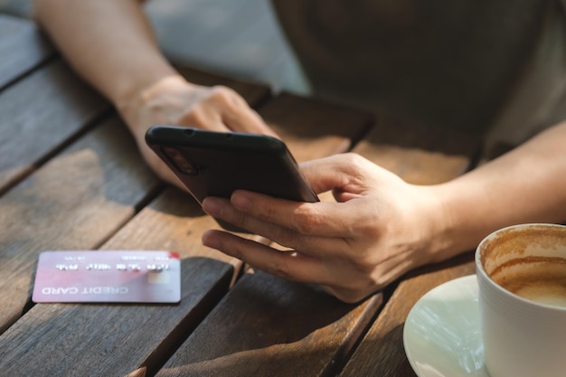 Zdjęcie kobieta robi zakupy online z kartą kredytową w kawiarni w outdoorclose up ręka trzyma smartphone