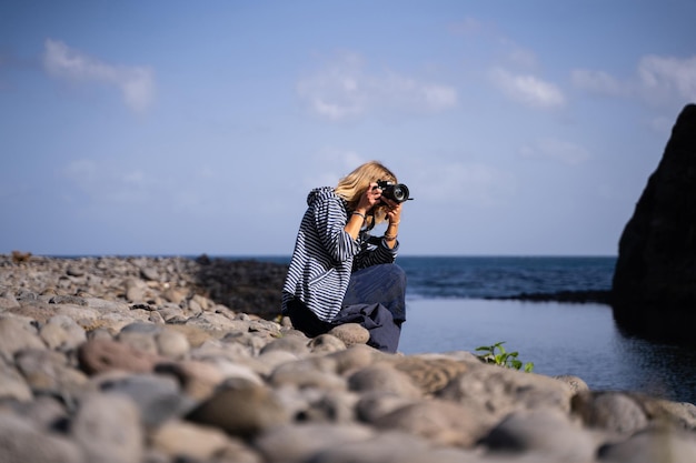 Kobieta robi zdjęcie morskiego krajobrazu aparatem cyfrowym