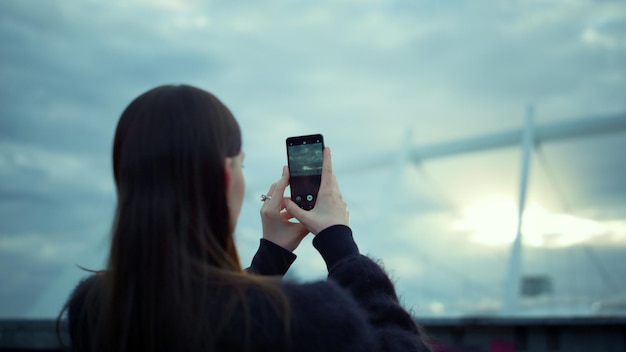 Kobieta robi zdjęcie na telefonie komórkowym na ulicy Brunetka dziewczyna za pomocą smartfona