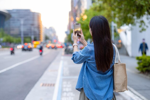 Kobieta robi zdjęcie na ulicy w mieście Taipei