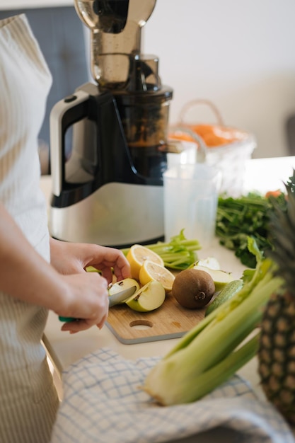 Zdjęcie kobieta robiąca napoje detoksykacyjne w domu produkty organiczne na drewnianym stole kobieta kroi jabłko i cytrynę