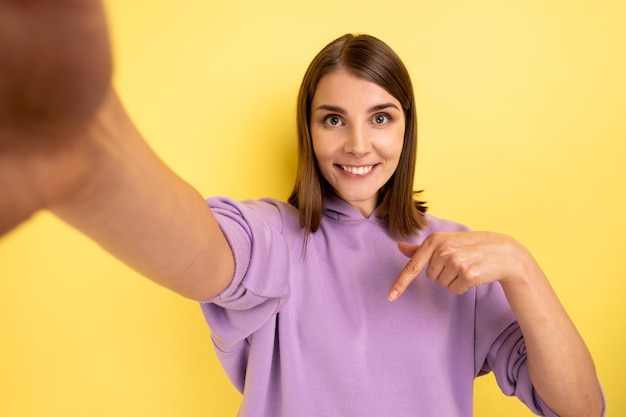 Kobieta robiąca selfie z punktu widzenia zdjęcia wskazującego palcem w dół poleca zasubskrybować jej vlog