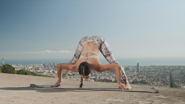 Kobieta rozciągająca ciało w punkcie widzenia BarcelonyAthletic dziewczyna robi joga w mieście