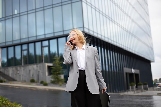 Kobieta rozmawia przez telefon komórkowy, chodząc po ulicy, patrząc od hotelu Koncepcja technologii